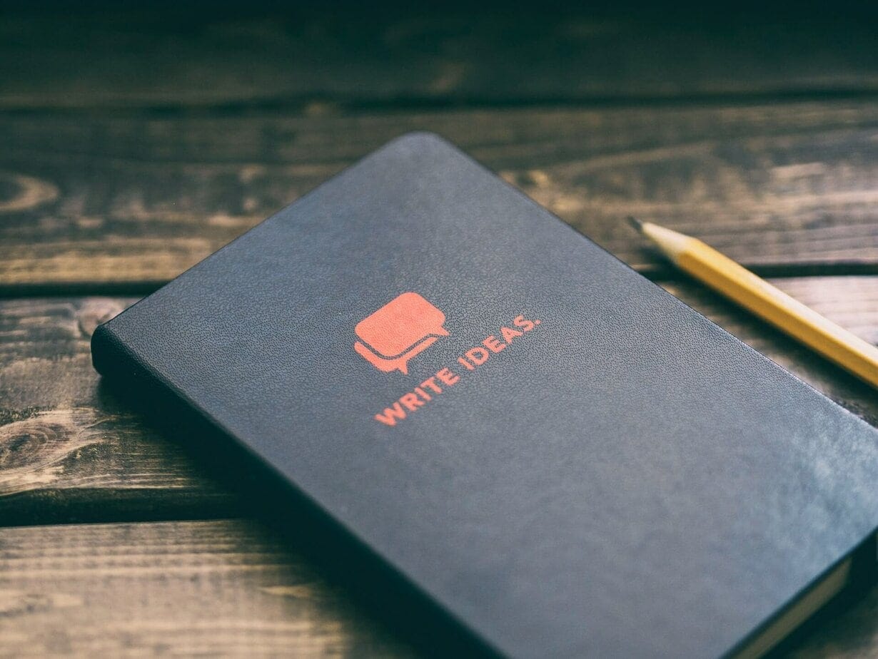 Foto de un escritorio con pluma, cuaderno y libros